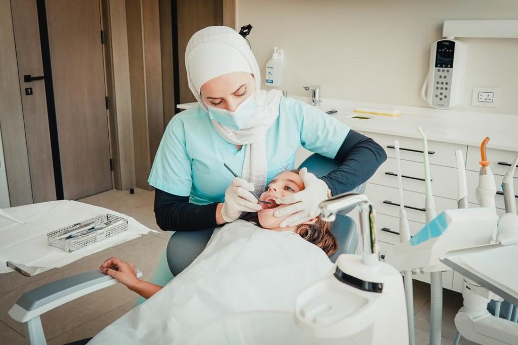 Pediatric dentist applying dental sealant at Abu Maizar Dental Center.